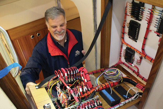 Larry Graf shows off the electrical wiring systems of an Aspen 40 being built at the Burlington factory at the time of this writing. The king-size berth of the master stateroom is around the corner to his left.